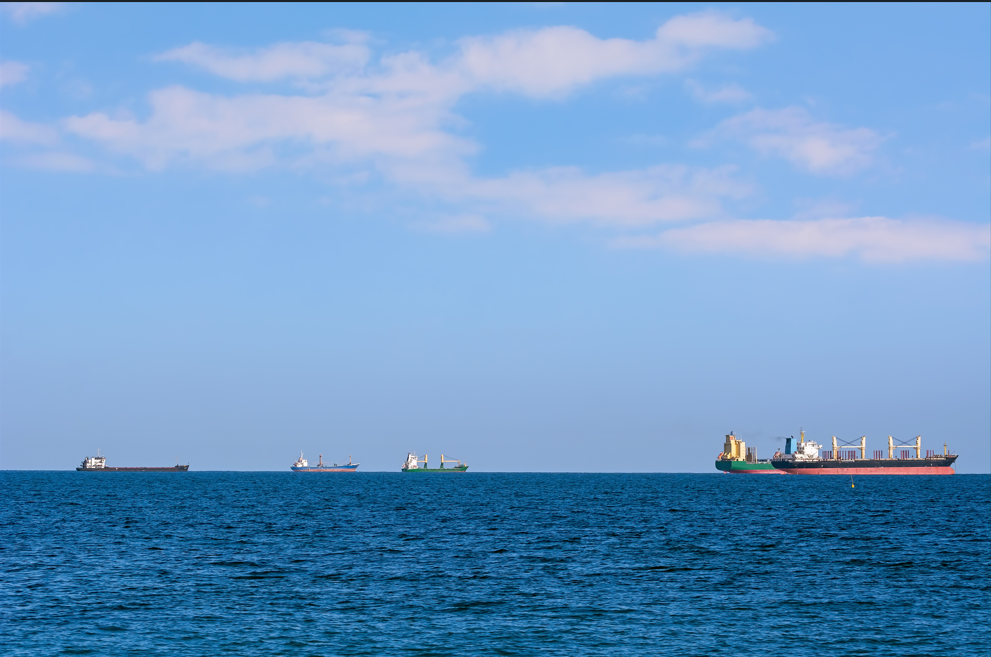 Handelsfartyg syns på ett blått hav med blå himmel