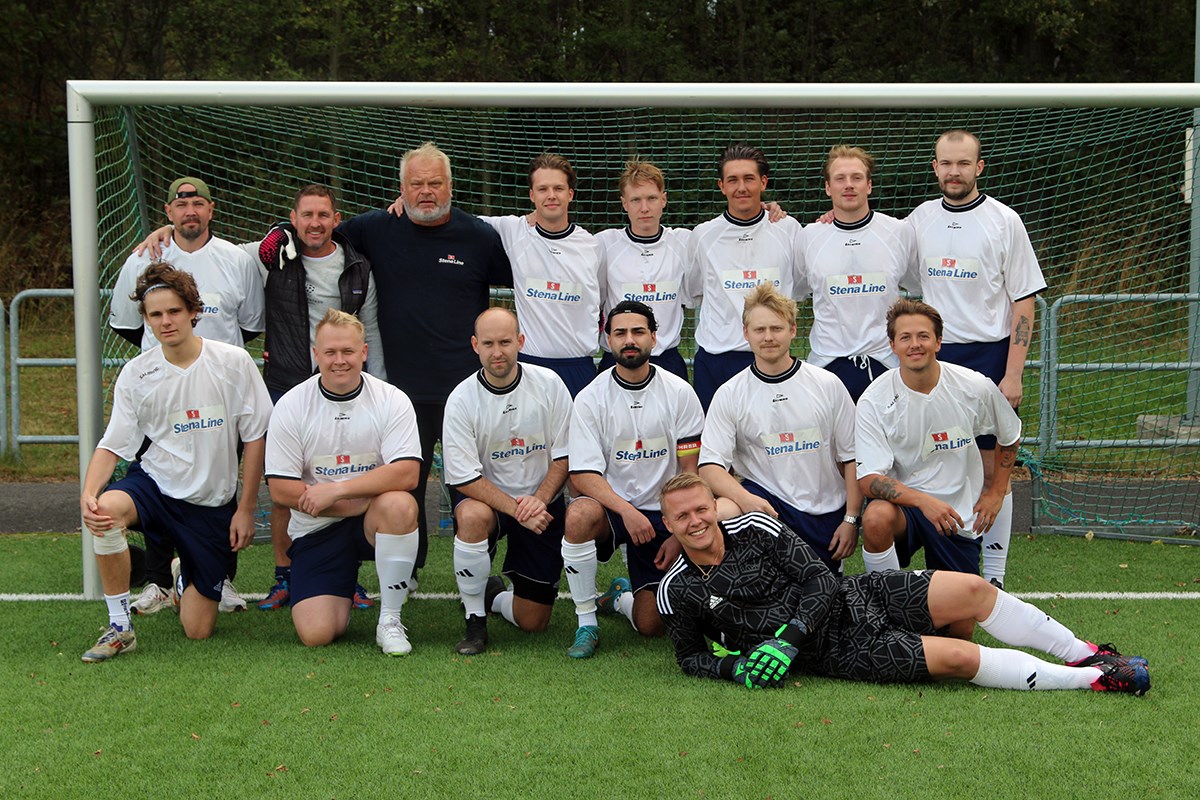 Ett fotbollslag i vita dressar står uppställda i målet