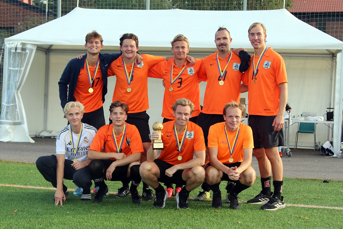 Vinnarlaget, klädda i orange dressar, poserar med segerpokalen.