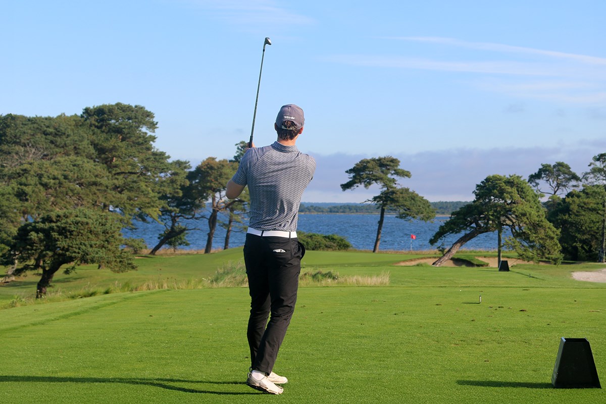 Golfspelare har svingat klubban och skjutit bollen tillsynes rakt ut mot havet