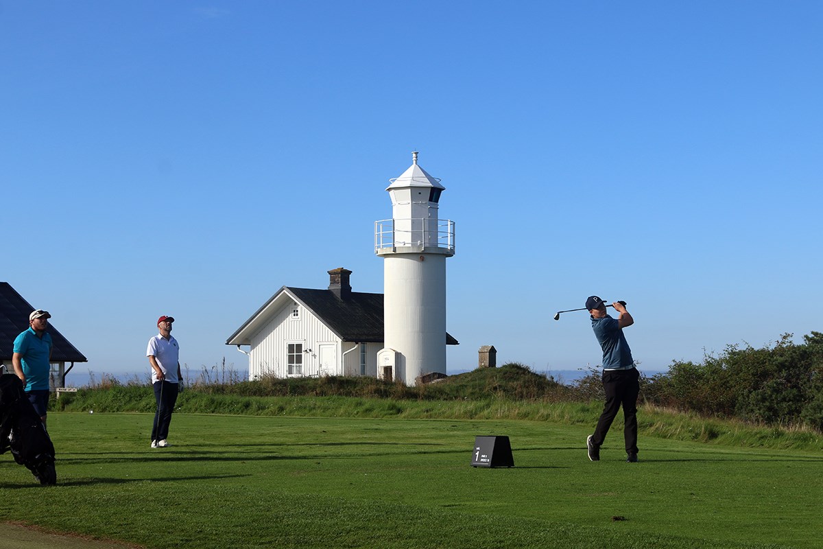 Tre golfspelare i bild, i bakgrunden (i mitten) syns en vit fyr.