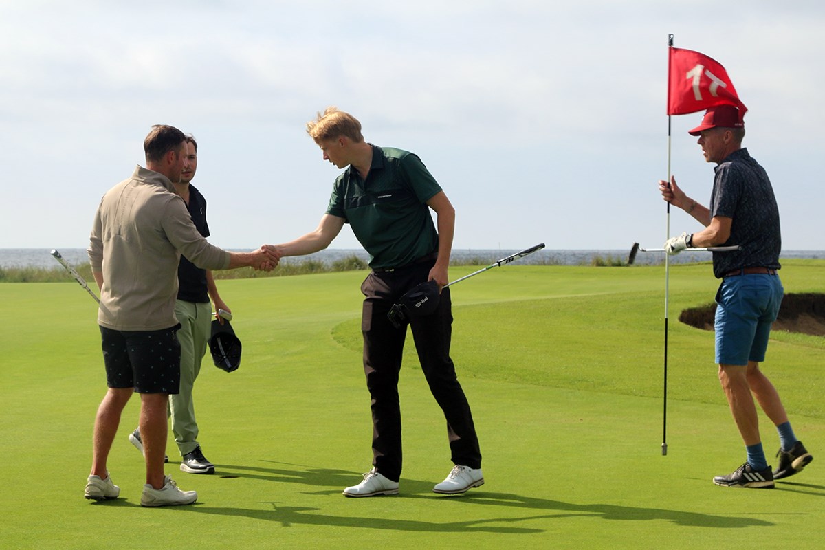 Tre spelare skakar hand, den fjärde bär en hålflagga
